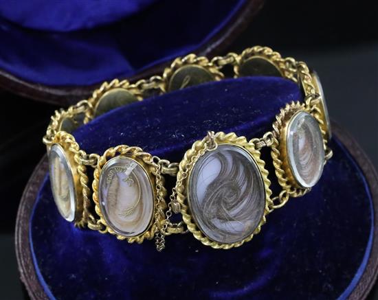 A cased Victorian gold and glazed plaited hair oval panel family memento bracelet,